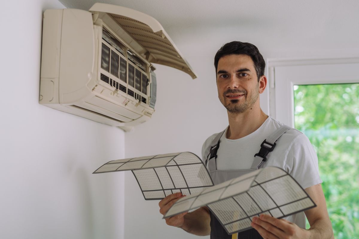 worker cleaning filters on home air conditioner indoor unit